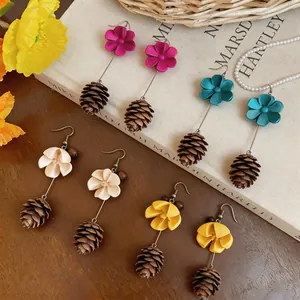 Detailed view of handmade flower and pinecone earrings in various colors on a vintage book