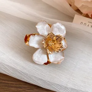 Detailed macro view of an elegant white enamel flower earring with a textured golden stamen