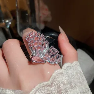 Close-up of a luxury silver butterfly ring with micro-pave pink stones on a finger.