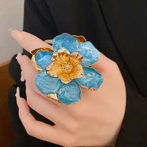 Large vintage blue and gold flower ring with oil-dripped petals shown on a hand.