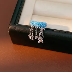 Elegant blue zircon beaded tassel ear cuff with heart charms shown on a jewelry box edge
