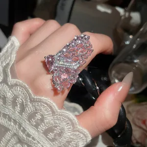 Detailed close-up of an elegant pink butterfly cocktail ring on index finger.
