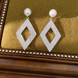 Gros plan d'élégantes boucles d'oreilles en argent avec perles et zircons pavés.