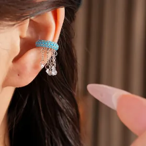 Close-up of blue turquoise studded ear cuff with silver tassel chains on ear