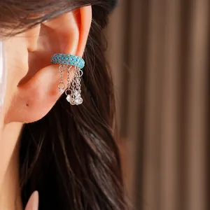 Close-up of turquoise beaded ear cuff with silver tassel chains on a model's ear.