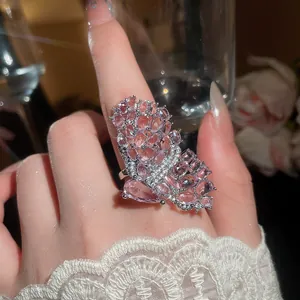 Macro view of a luxury pink crystal butterfly ring on a delicate finger with lace sleeve.