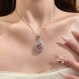 Close-up detail of elegant teardrop necklace with pink zircon pendant on model's neck.