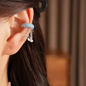 Close-up detail of blue zircon ear cuff with silver tassels worn on ear