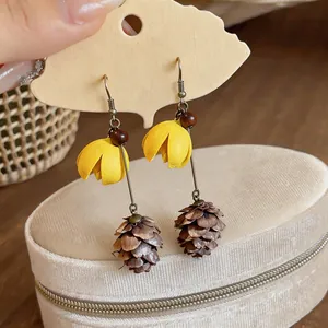 Detail of summer style earrings featuring yellow flowers and pinecone-shaped tassels
