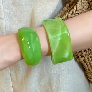 Detailaufnahme grüner Marmor-Armreifen aus Acryl am Handgelenk vor Leinenhintergrund