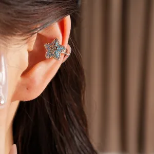 Close-up of a silver star-shaped ear cuff set with blue zircon stones on ear