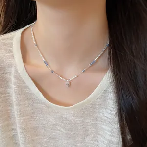 Close-up of a delicate crystal and pearl beaded necklace with a square pendant