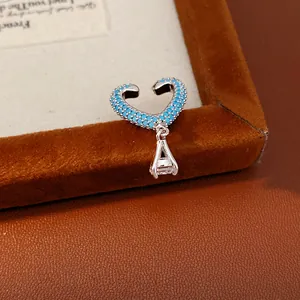 Detailed macro view of heart-shaped ear cuff featuring blue zircons and dangling crystal