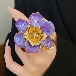 Detailed close-up of a large purple floral ring with gold accents and marble texture