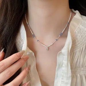 Detail of square crystal pendant on a pearl and blue bead necklace