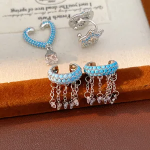 Macro detail view of blue zircon stones and silver-tone chain tassels on ear cuffs