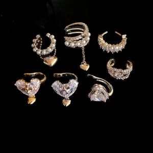 Macro detail of various silver ear cuffs with sparkling zircons and delicate heart charms.