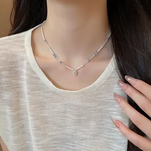Close-up of delicate crystal bead necklace with square pendant on model's neck.