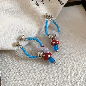 Macro detail of cute mushroom and flower charms on retro blue beaded hoop earrings