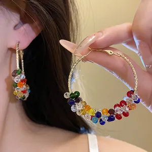 Detail of dopamine-colored crystal beaded gold hoop earrings for a luxury summer look