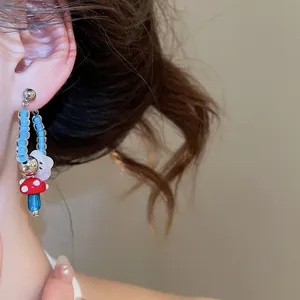 Close-up of retro mushroom earring with blue glass beads and a white flower detail