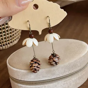 Detailed macro shot of floral and pinecone tassel drop earrings displayed on a velvet jewelry box