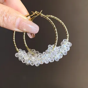 Close-up of sparkling clear crystal beads on large gold-tone hoop earrings