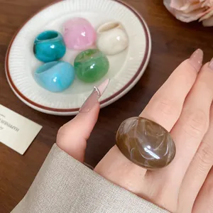 Close-up view of a stylish brown marbled resin ring worn on a woman finger for detail
