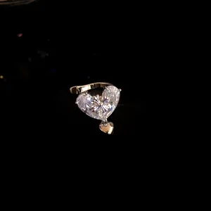 Close-up of a sparkling heart-shaped zircon ear cuff with a dangling small heart.