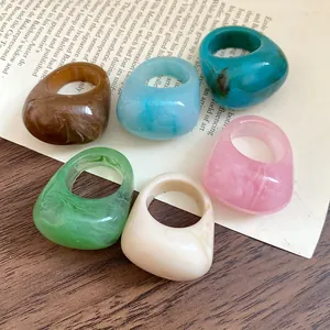 Detailed close-up showing six colorful marbled resin rings on a vintage book page