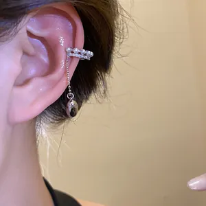 Detailed macro view of a silver pearl and zircon ear cuff with a dangling bean pendant