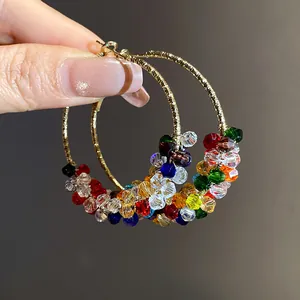 Detail view of colorful crystal beaded hoop earrings featuring a gold-toned textured finish