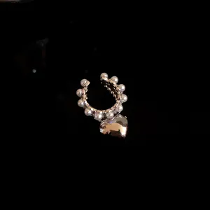 Detailed close-up of a silver heart charm ear cuff with pearl embellishments