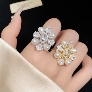 Détail macro de bagues élégantes en forme de fleurs avec perles et pierres zircon.