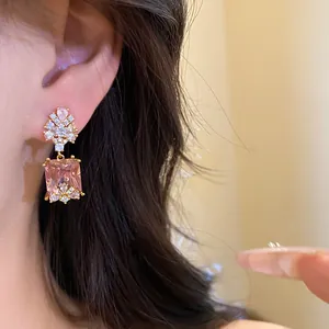 Close-up view of vintage pink square zircon pendant earrings worn on an ear