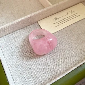 Macro shot of pink marbled resin ring with smooth geometric design for women