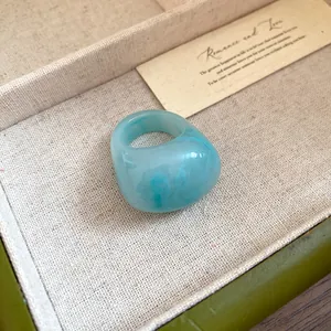 Detail shot of a minimalist blue marbled resin ring with a smooth polished finish.