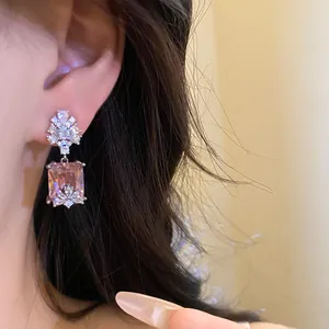 Detailed macro view of vintage square pink zircon pendant earring worn on an ear