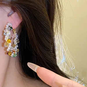 Close-up shot of vibrant colorful crystal and pearl beaded hoop earrings worn on ear