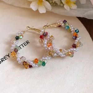 Close-up of colorful crystal and pearl beaded hoop earrings on a wooden background