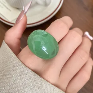 Detailed close-up of a minimalist green oval resin ring worn on a finger for women