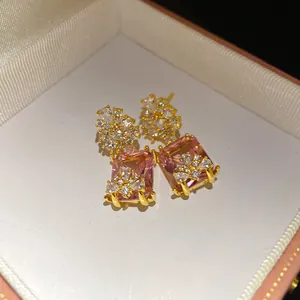 Detailed macro view of vintage gold-plated drop earrings with square pink zircon stones