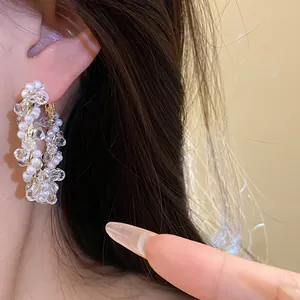 Macro detail shot of white pearl and clear crystal beaded hoop earring worn on earlobe