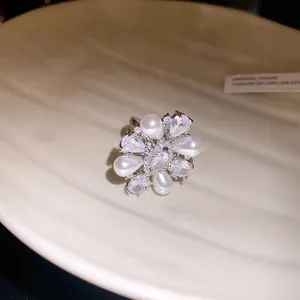 Gros plan d'une bague ouverte plaquée or 14k avec perles et design floral en zircon