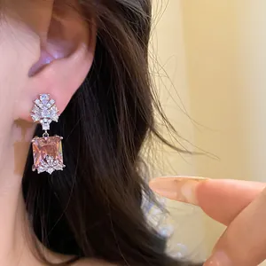 Close-up view of vintage court style silver earrings with a square pink zircon pendant