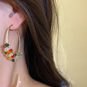 Detail shot of vibrant multicolored crystal beaded hoop earrings worn on the ear