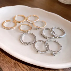 Elegante goldene und silberne offene Ringe mit Perlen und Strass auf einem Teller.