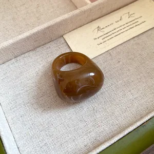 Detailed view of an amber resin ring with a marbled pattern on a linen background