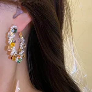 Close-up macro detail of vibrant colorful crystal and pearl beaded hoop earrings
