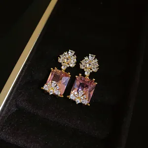 Detailed macro view of vintage-style gold earrings with rectangular pink zircons.